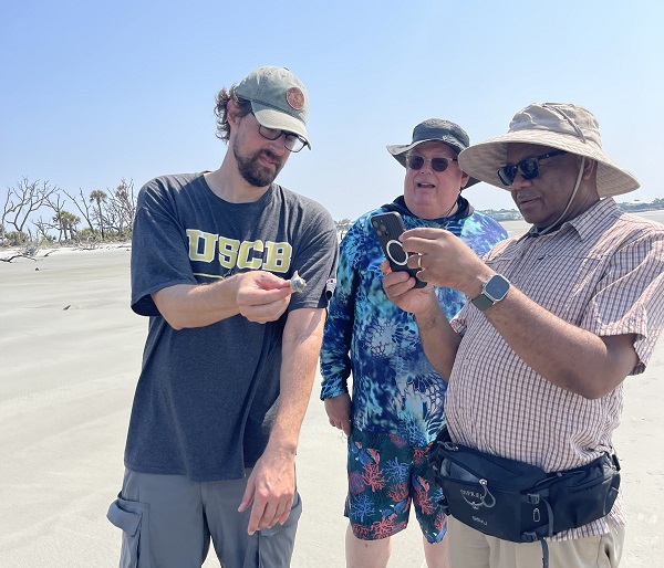 Researchers and Chancellor Taking Photo of Beach Object